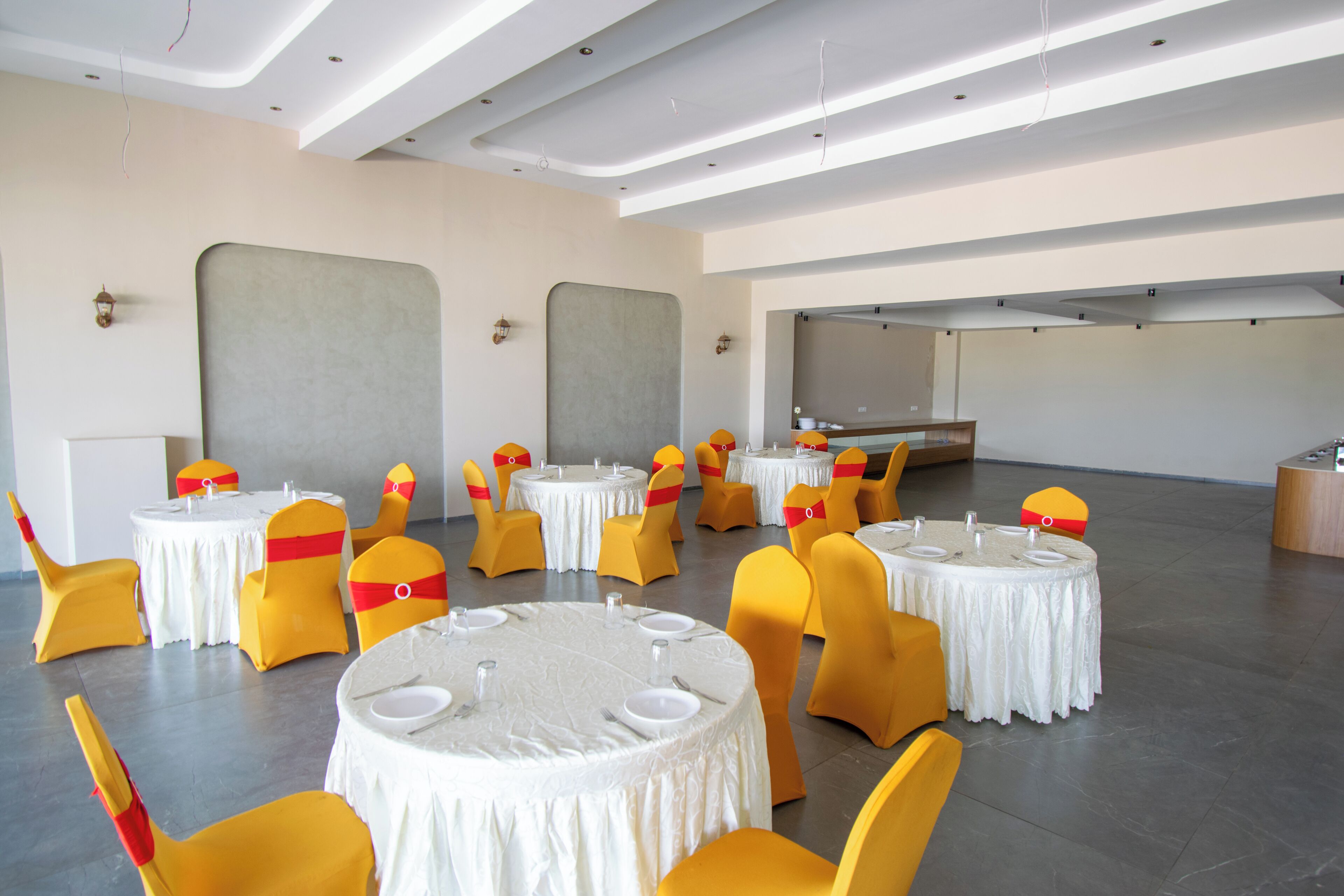 A spacious room with multiple round tables and yellow chairs, arranged for a formal event.