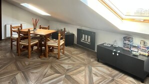 Ein modernes Schlafzimmer im Loft-Stil mit Dachfenster, Holzboden, einem Essbereich und einem Medienregal.