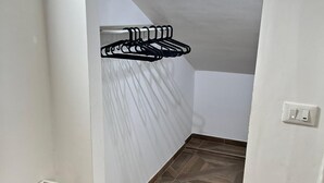 Ein Zimmer mit einem Holzboden mit Fischgrätmuster, einem weißen Heizkörper und einem schwarzen Wäscheständer.