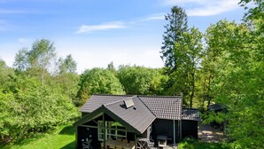 Een chalet met schuin dak, een terras en een patio met tuinmeubilair.