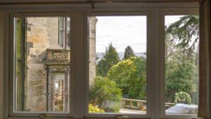 Blick durch ein Fenster auf ein Gebäude aus Stein und grüne Vegetation.