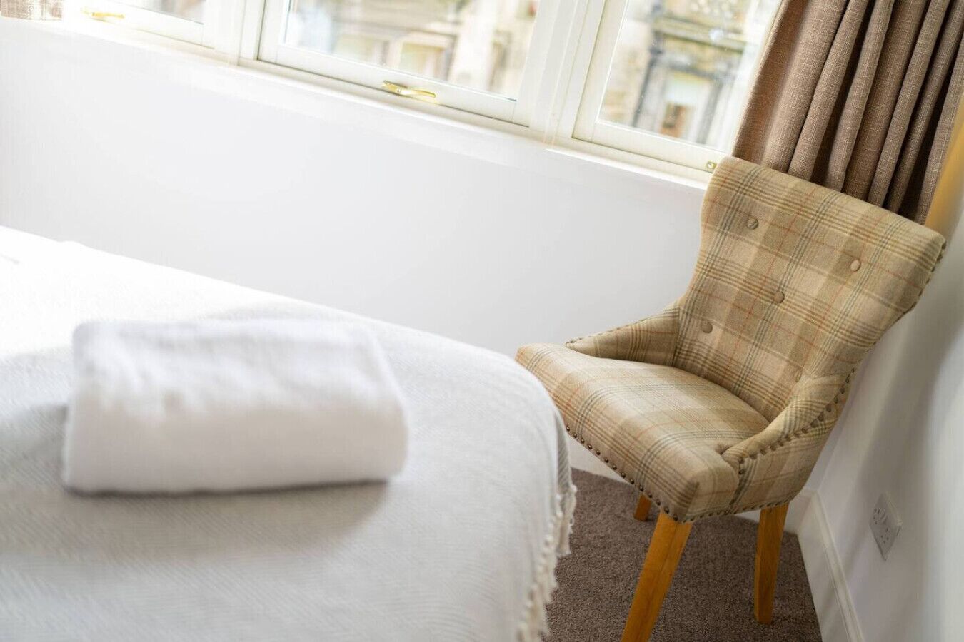 Une chambre d’hôtel avec un lit, une chaise et une fenêtre avec des rideaux.