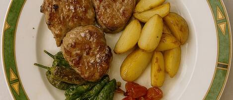 Un plato con carne a la parrilla, patatas asadas y verduras.