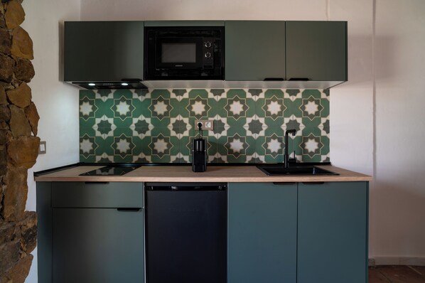 Una cocina compacta con microondas, lavavajillas y un salpicadero decorado.