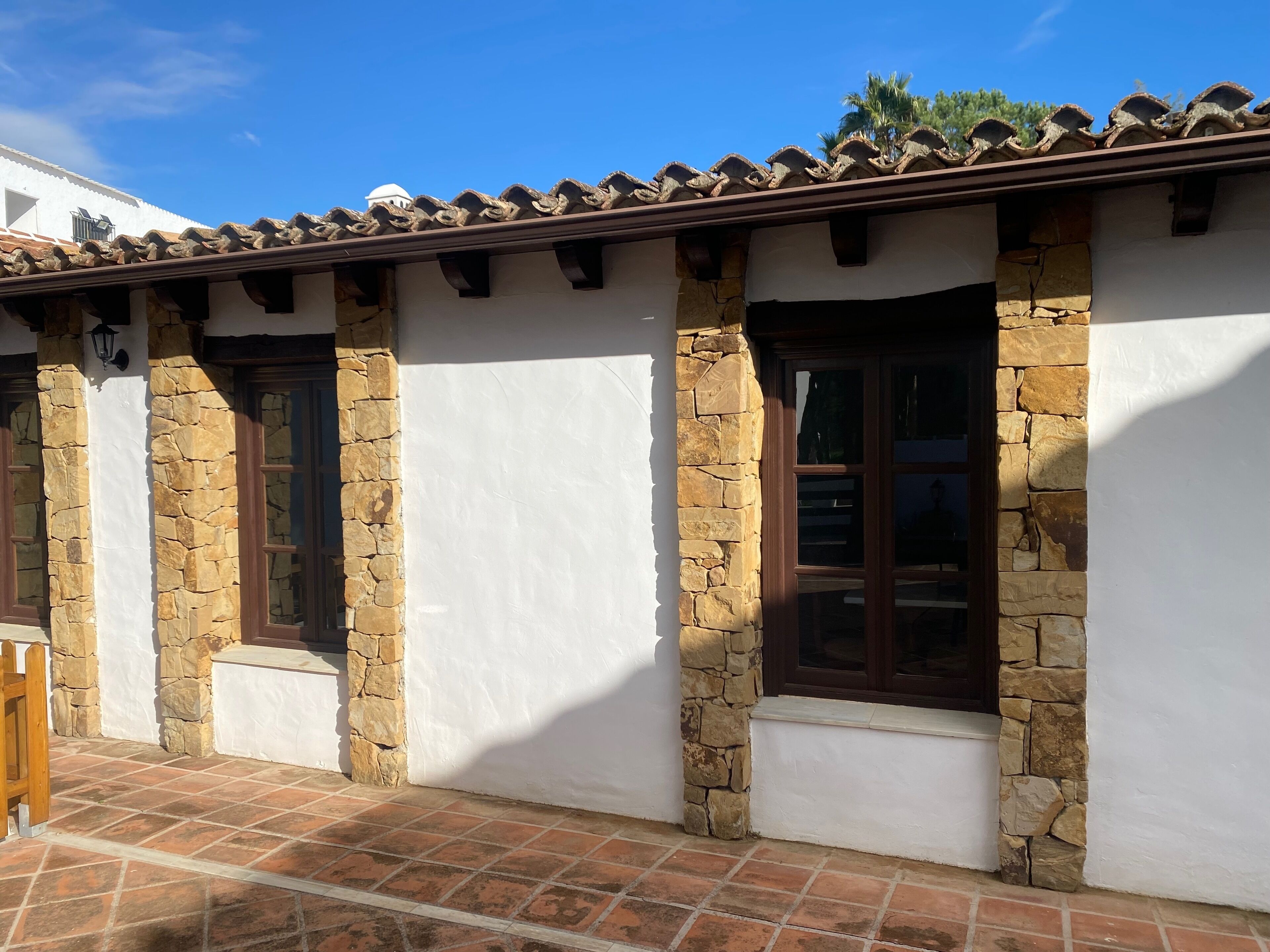Un bâtiment doté de piliers en pierre, de murs blancs et d’un toit recouvert de tuiles.
