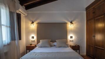 Un dormitorio con una cama grande, dos mesitas de noche, un armario de madera e iluminación en la pared.