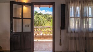Una puerta que da a un espacio exterior con vistas a un muro de ladrillo y vegetación.