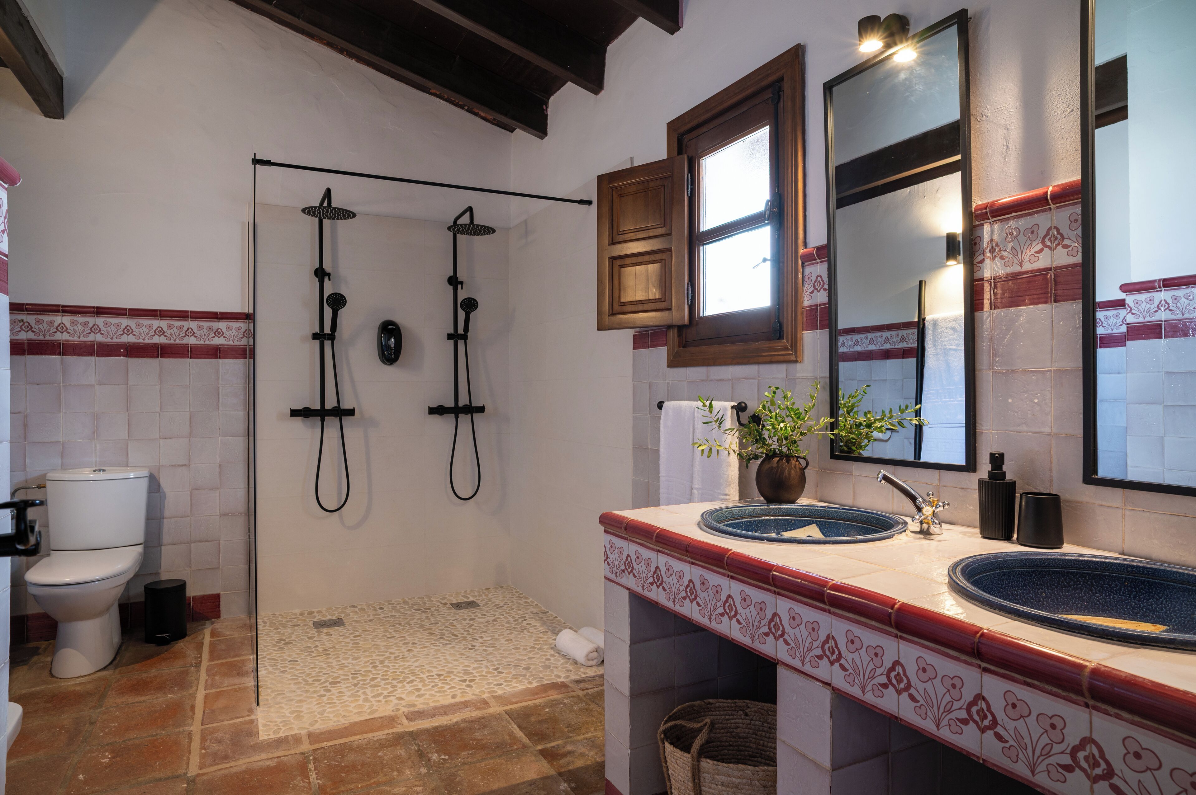A bathroom with two sinks, a shower, and a toilet.