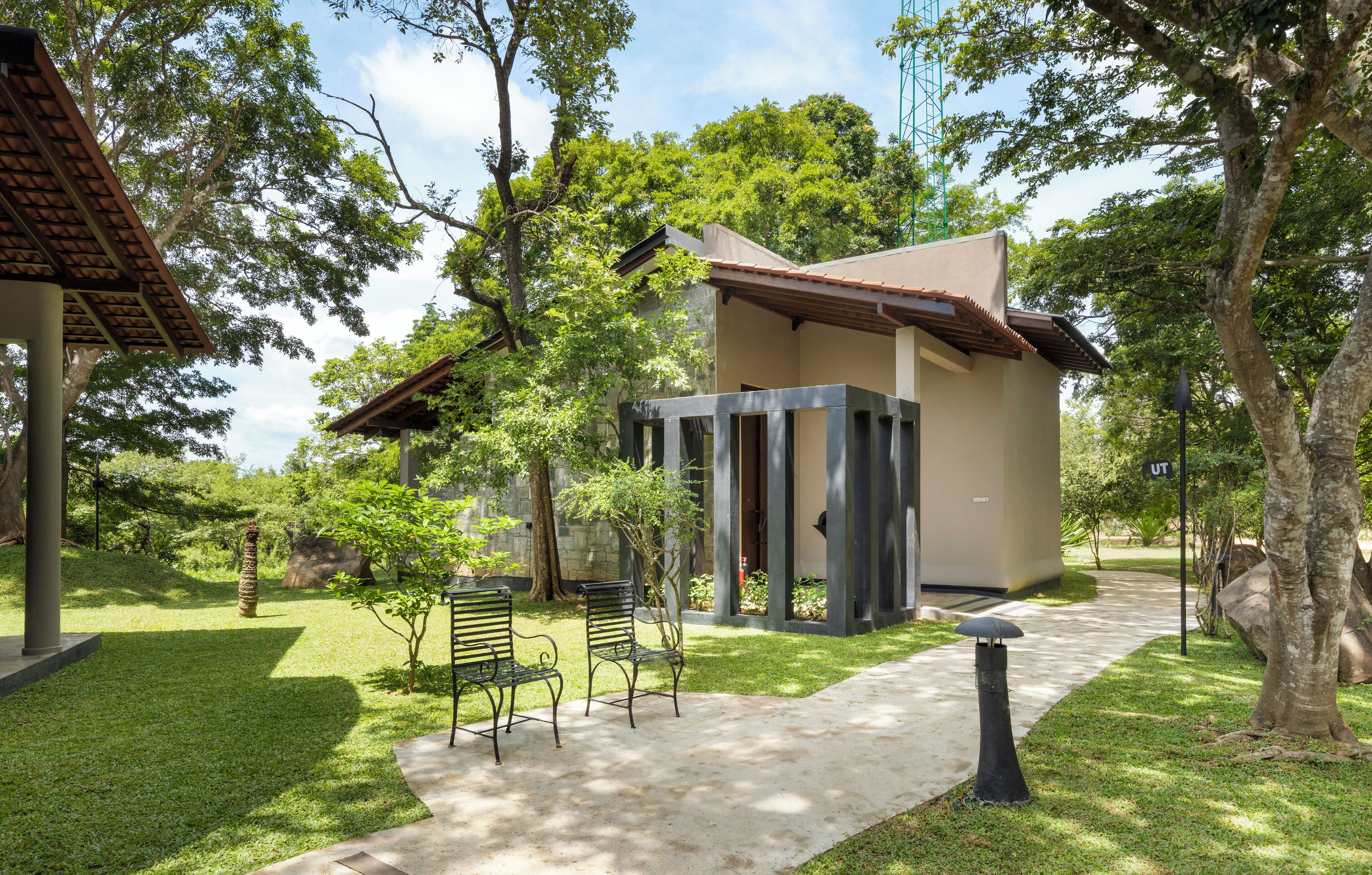 Um edifício moderno com fachada de concreto, rodeado por vegetação exuberante e árvores.