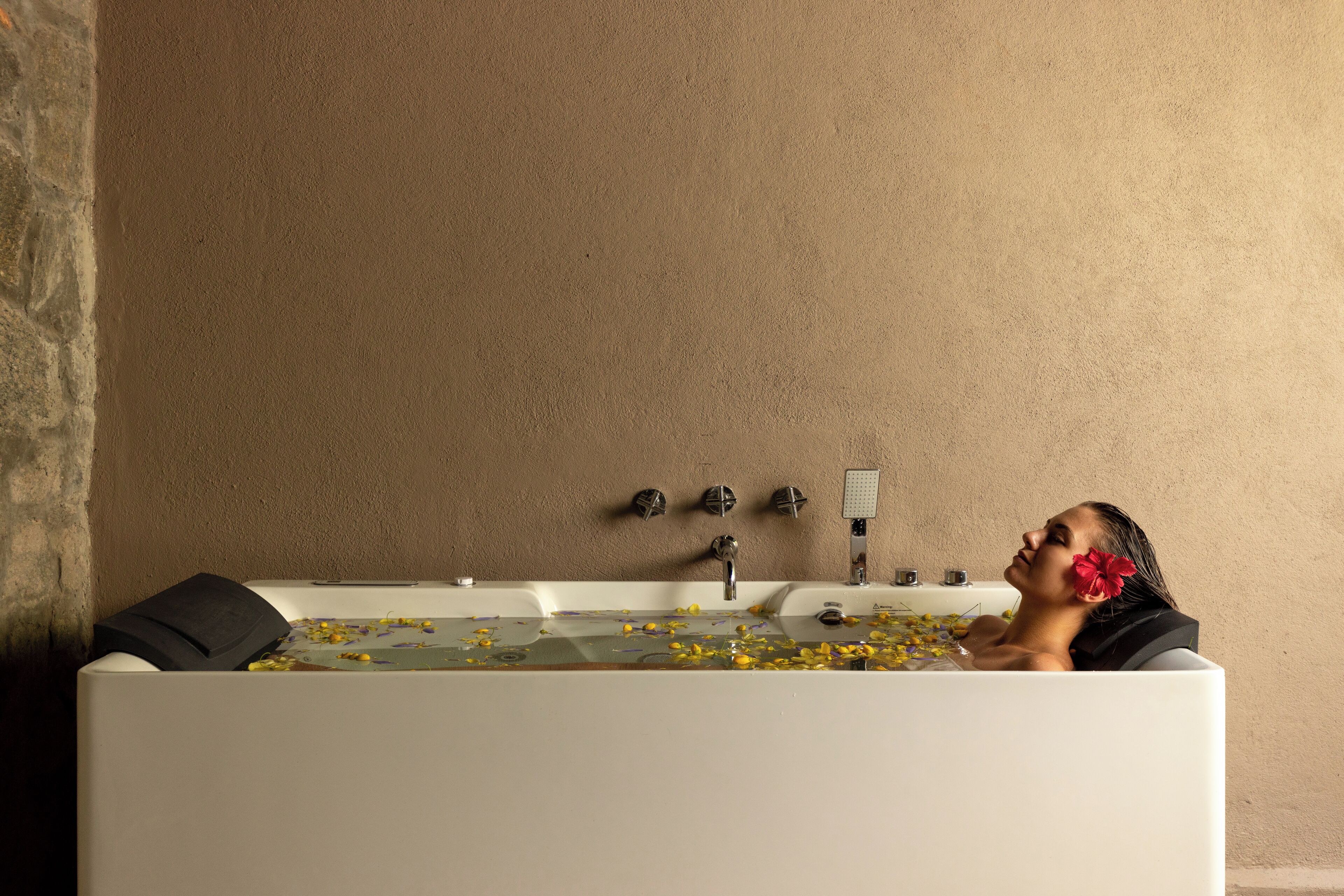 A bathtub with flowers and a person relaxing in it.
