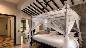 A bed with a canopy, a stone wall, and a wooden floor. - Ayugiri Ayurveda Wellness Resort  (Sigiriya)