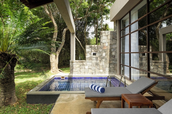 A pool area with lounge chairs and a stone wall. - Ayugiri Ayurveda Wellness Resort (Sigiriya)