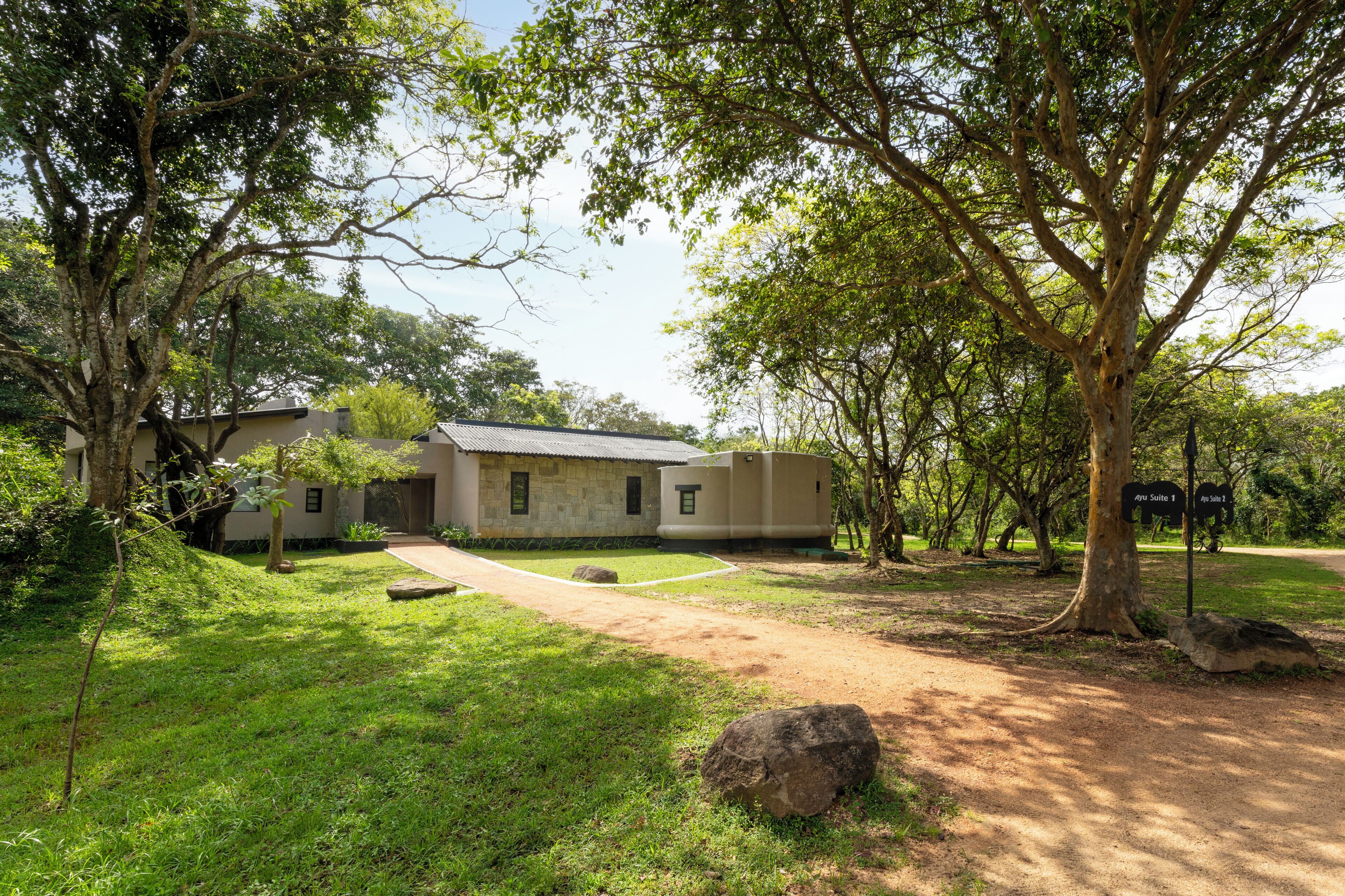 A building with a stone facade, surrounded by lush greenery and trees.