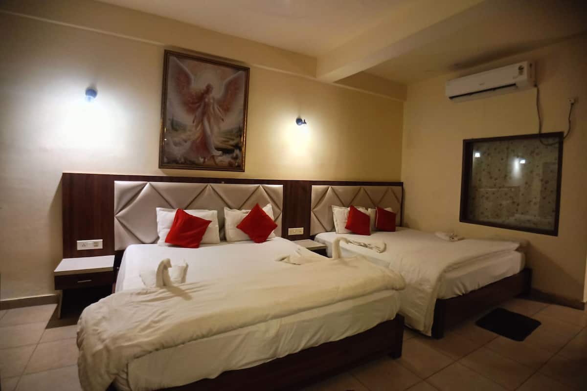 A hotel room with two beds, a painting on the wall, an air conditioning unit, and a window.