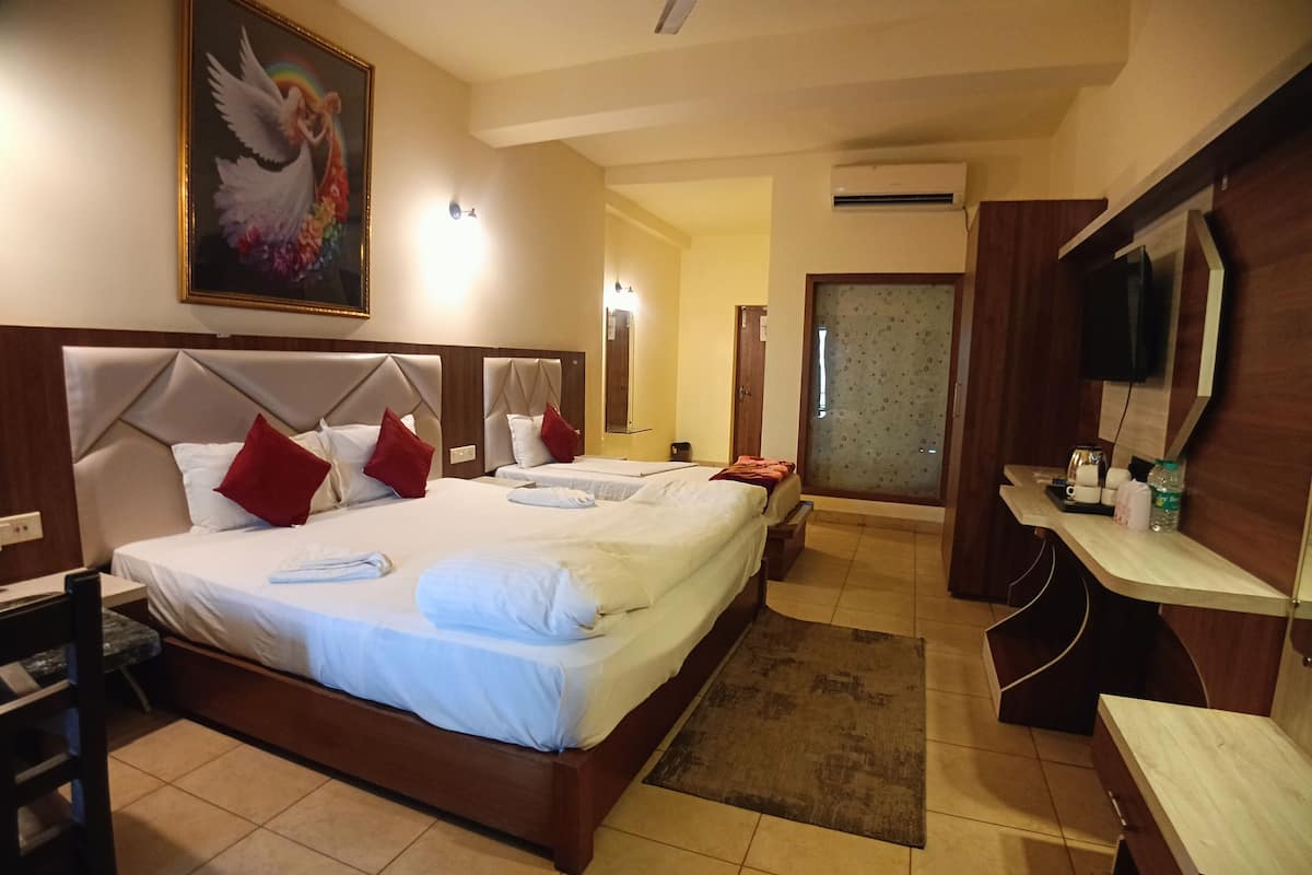 A hotel room with a large bed, a desk, a chair, a television, and a bathroom visible through a door.