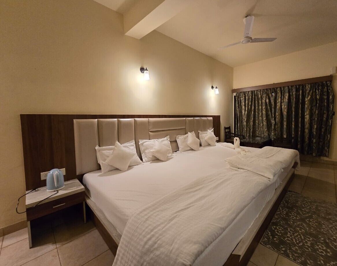 A large bed with a headboard, a bedside table with a lamp, and a ceiling fan.
