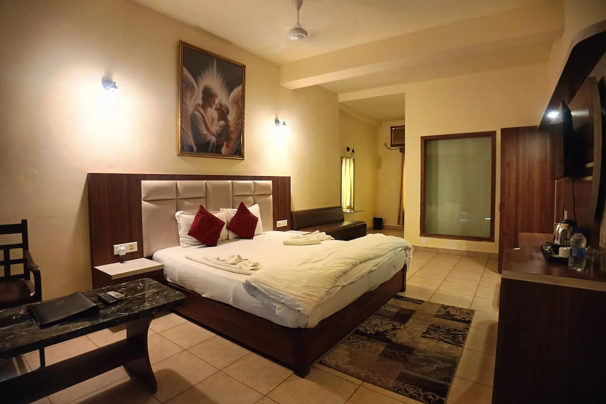 A hotel room with a large bed, a desk, a chair, a TV, and a painting on the wall.