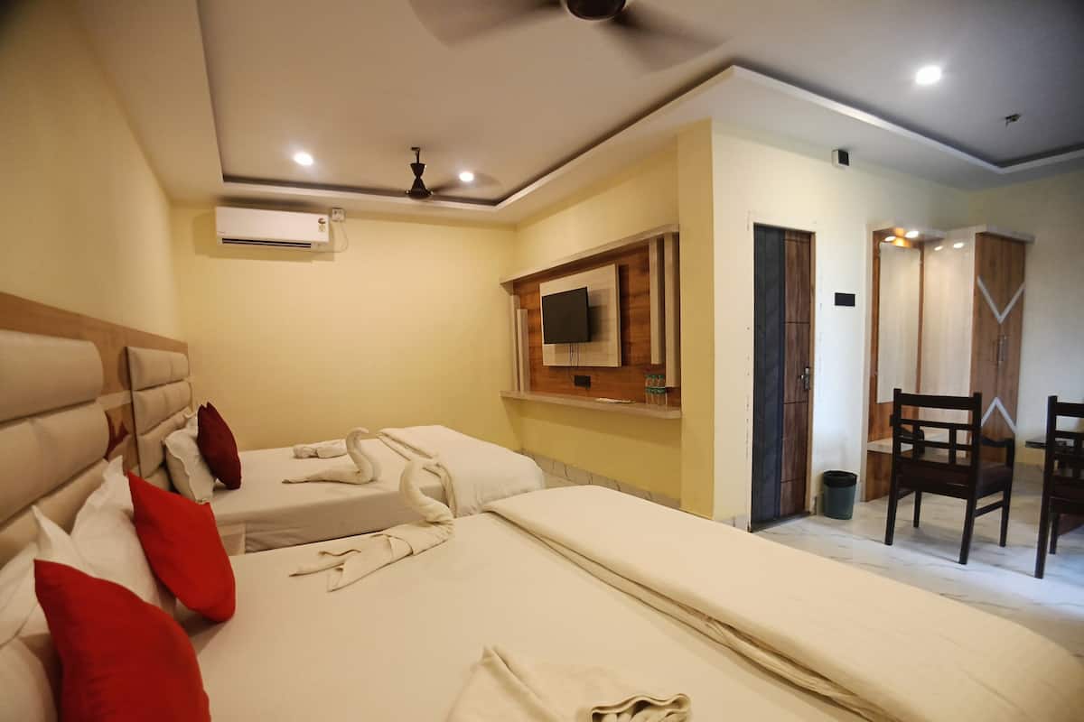 A hotel room with two beds, a TV mounted on the wall, a ceiling fan, and a wooden door.