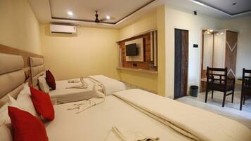 Habitación de hotel con dos camas, un televisor montado en la pared, un ventilador de techo y una puerta de madera.