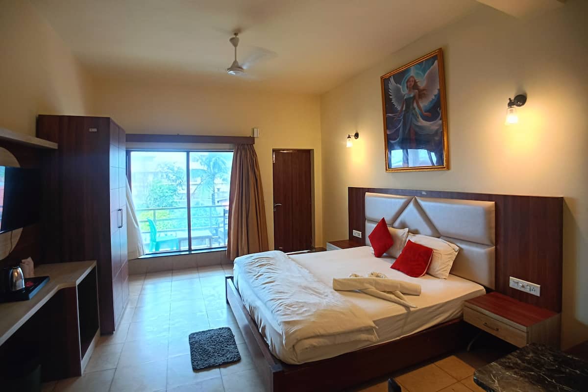 A hotel room with a bed, a desk, a television, a painting, and a view of the outdoors.