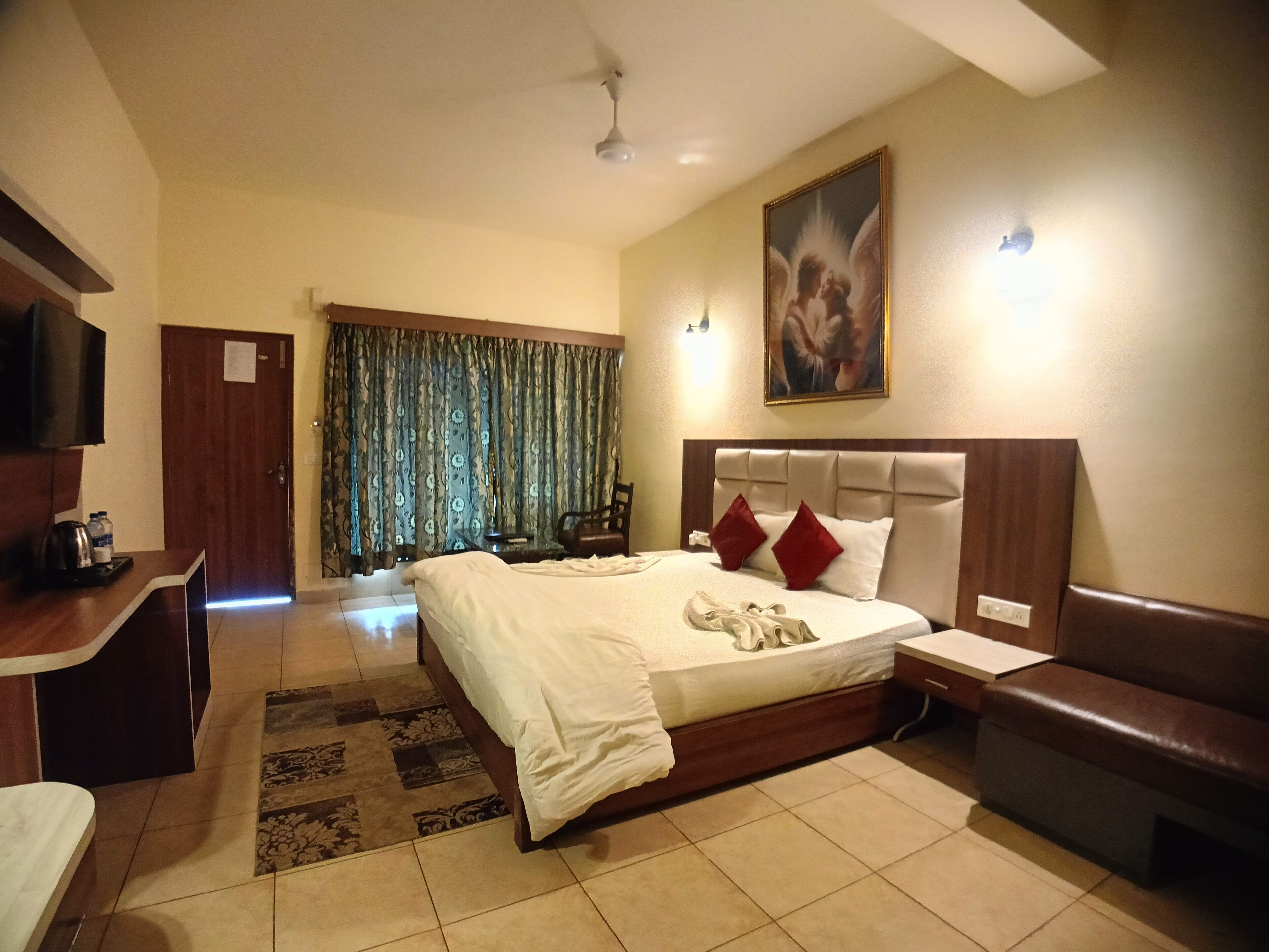 A hotel room with a bed, a desk, a chair, a sofa, and a television.