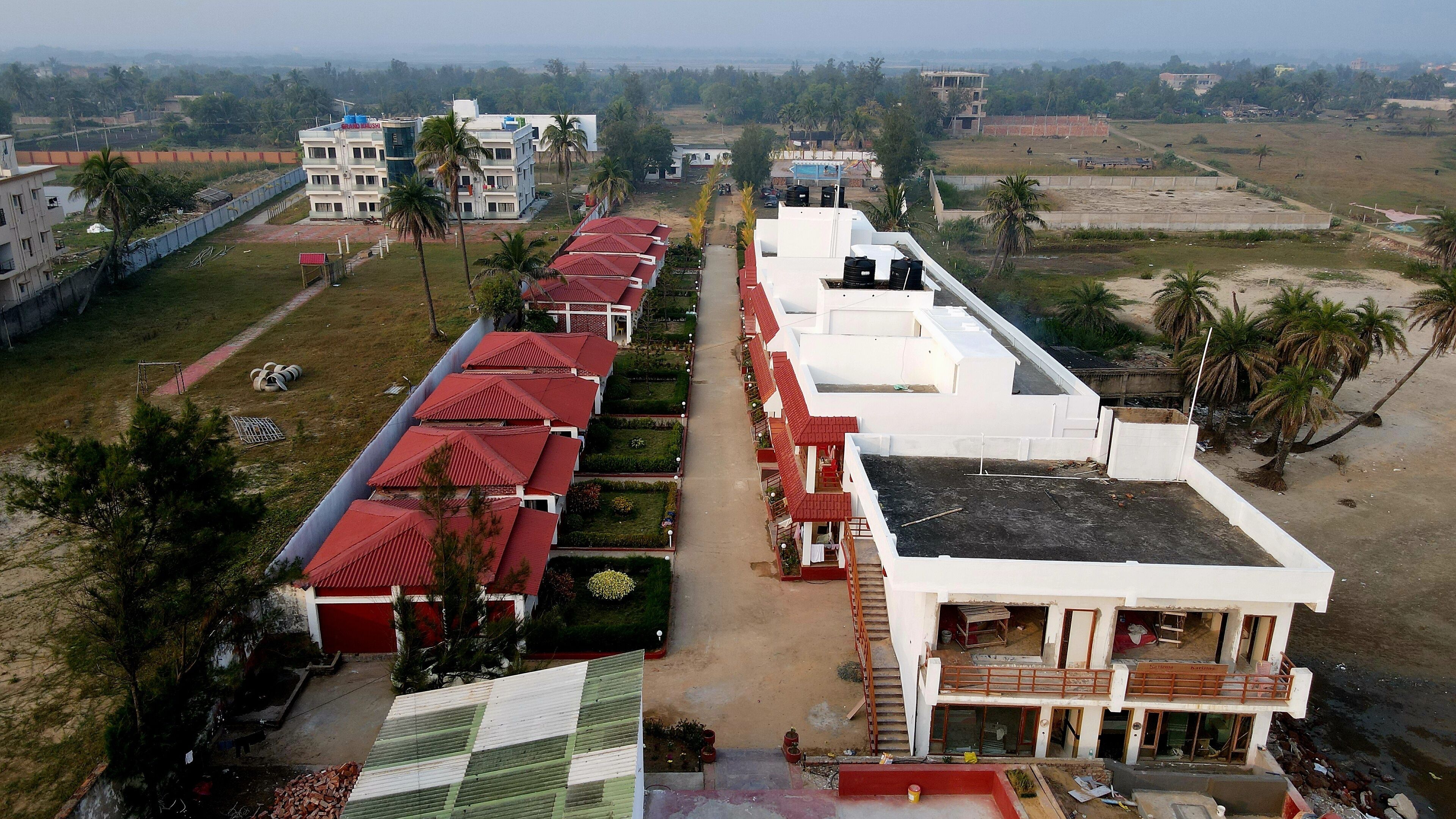 A multi-story hotel with a central courtyard, surrounded by greenery and palm trees.