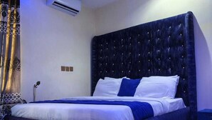 A modern bedroom with a large bed, air conditioning unit, and decorative curtains. - Esthercy Hotels Ltd Lagos (Lagos)