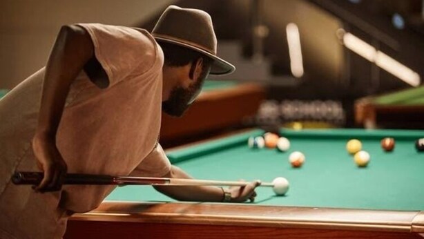 A person playing pool at a table with a green felt surface and a white cue ball. - Esthercy Hotels Ltd Lagos (Lagos)
