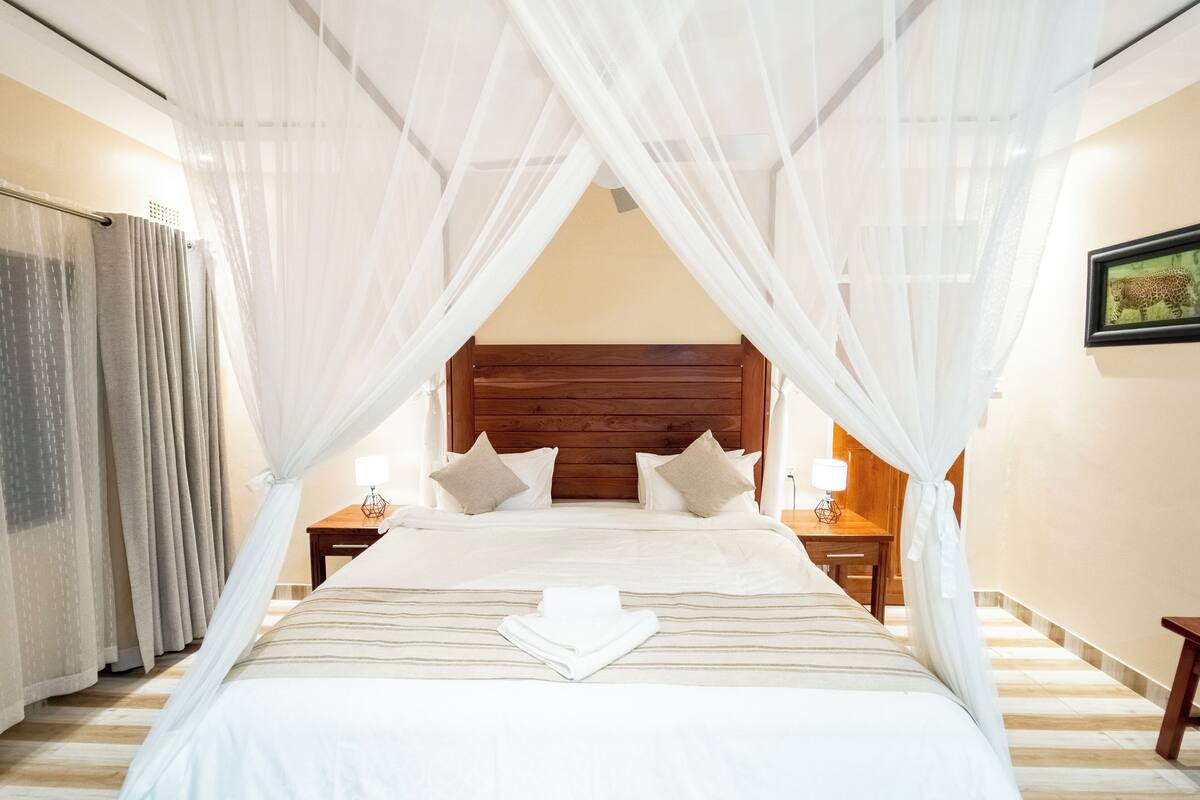 A neatly made bed with a wooden headboard, white bedding, and a pair of bedside lamps.