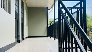 A covered outdoor area with a tiled floor, a black metal railing, and a clear sky in the background. - Sunset Inn Arusha (Arusha)