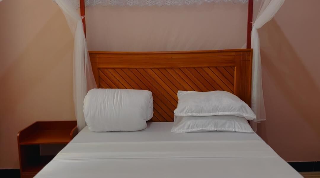 Un letto con una testiera in legno, biancheria da letto bianca e un comodino.
