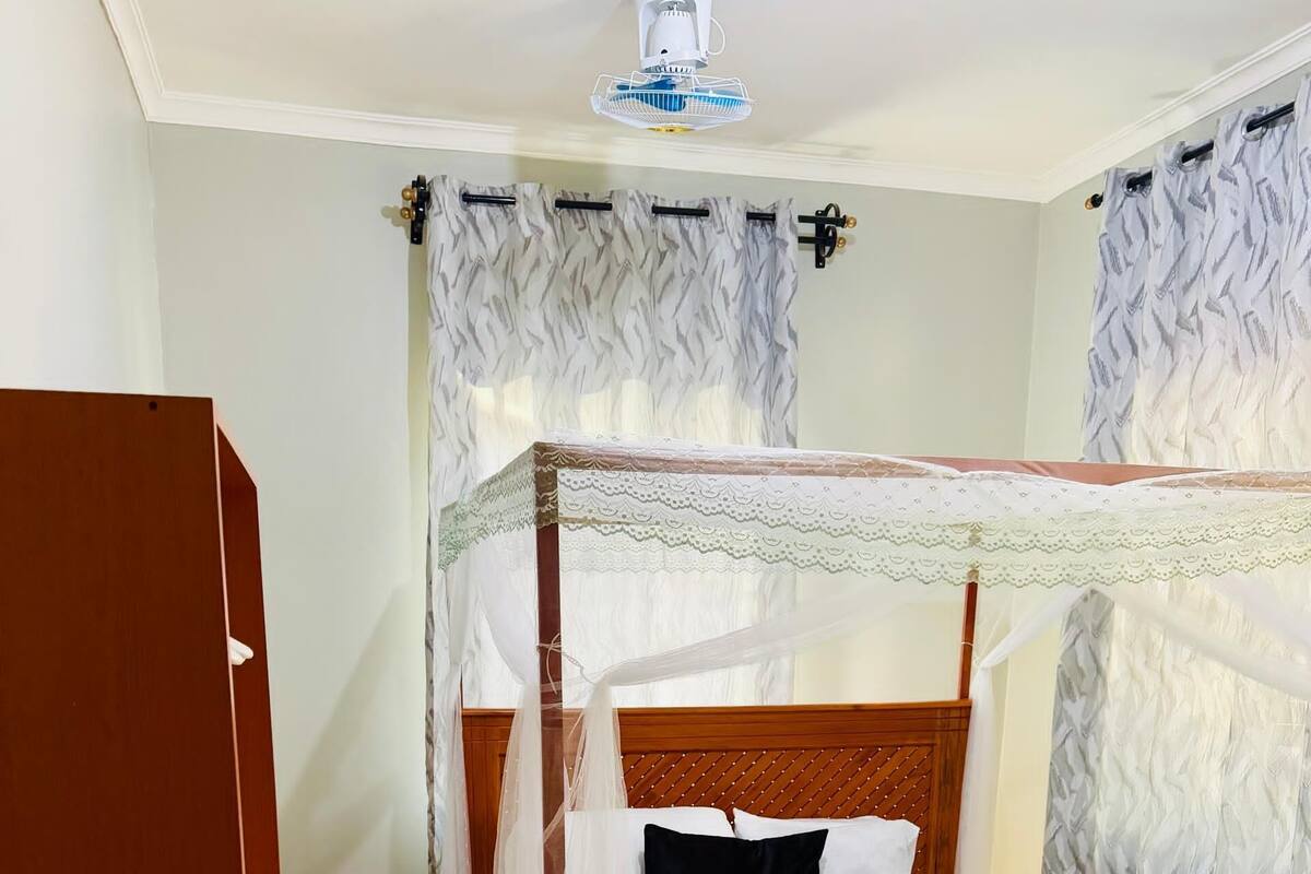 A bedroom with a wooden four-poster bed, a canopy, and a ceiling fan.
