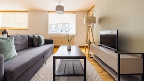 Un salon moderne avec un canapé, une table basse, un téléviseur et une lampe.