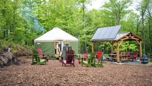 A campsite with a tent, a gazebo with solar panels, and several Adirondack chairs. - Cozy Yurt in the Woods (Sainte-Agathe-des-Monts)