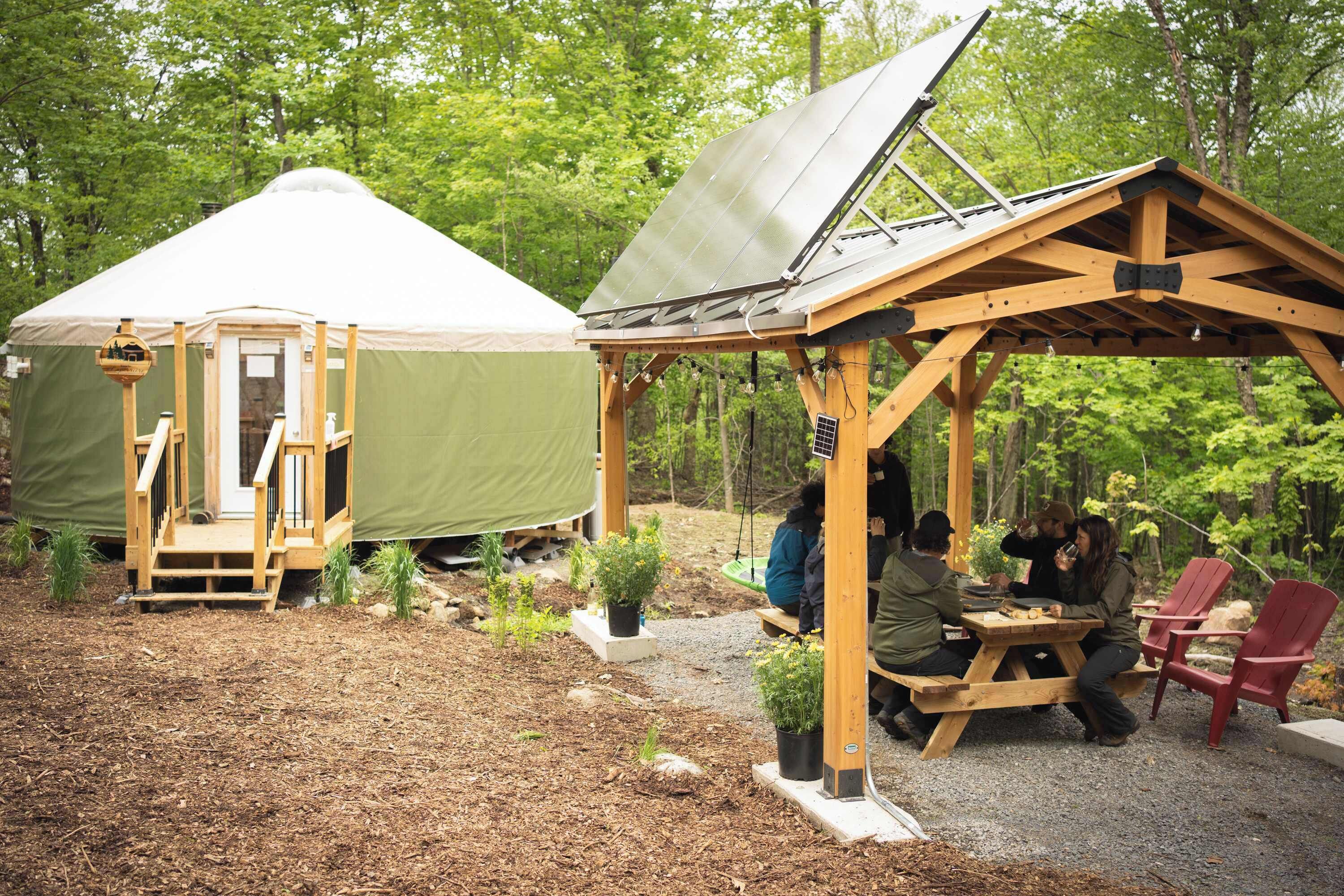 A rustic outdoor setting with a covered wooden structure and a tent.