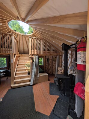 Un intérieur en bois avec un escalier, un extincteur et un petit coin salon.