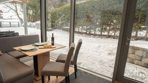 Een moderne eetruimte met een houten tafel, twee stoelen en een bank.