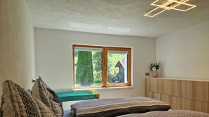 Een slaapkamer met een bed, een raam, een nachtkastje en een wandmeubel.