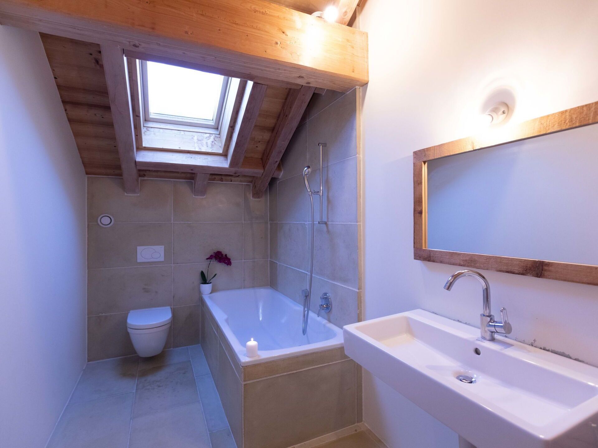 Un baño con tragaluz, una bañera, un inodoro y un lavabo con espejo.
