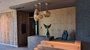 Una zona reception con una scrivania in legno, una sedia blu e una figurina decorativa a forma di angelo.