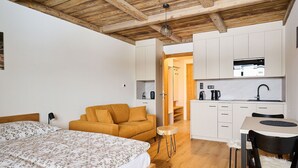 Una camera compatta con un letto, un divano, un tavolino e un angolo cottura.