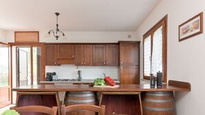 A kitchen with wooden cabinets, a granite countertop, and a dining area with a table and chairs. - Wonderful private villa with private pool, WIFI, TV, patio, pets allowed and panoramic view (Castel Del Piano)