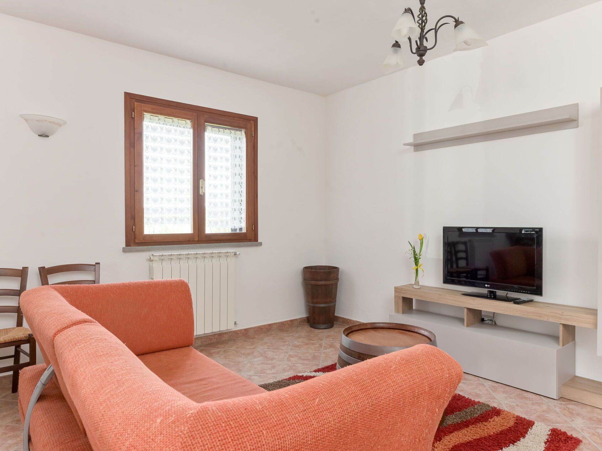 Una sala de estar moderna con un sofá, televisor, radiador, ventana y una araña.