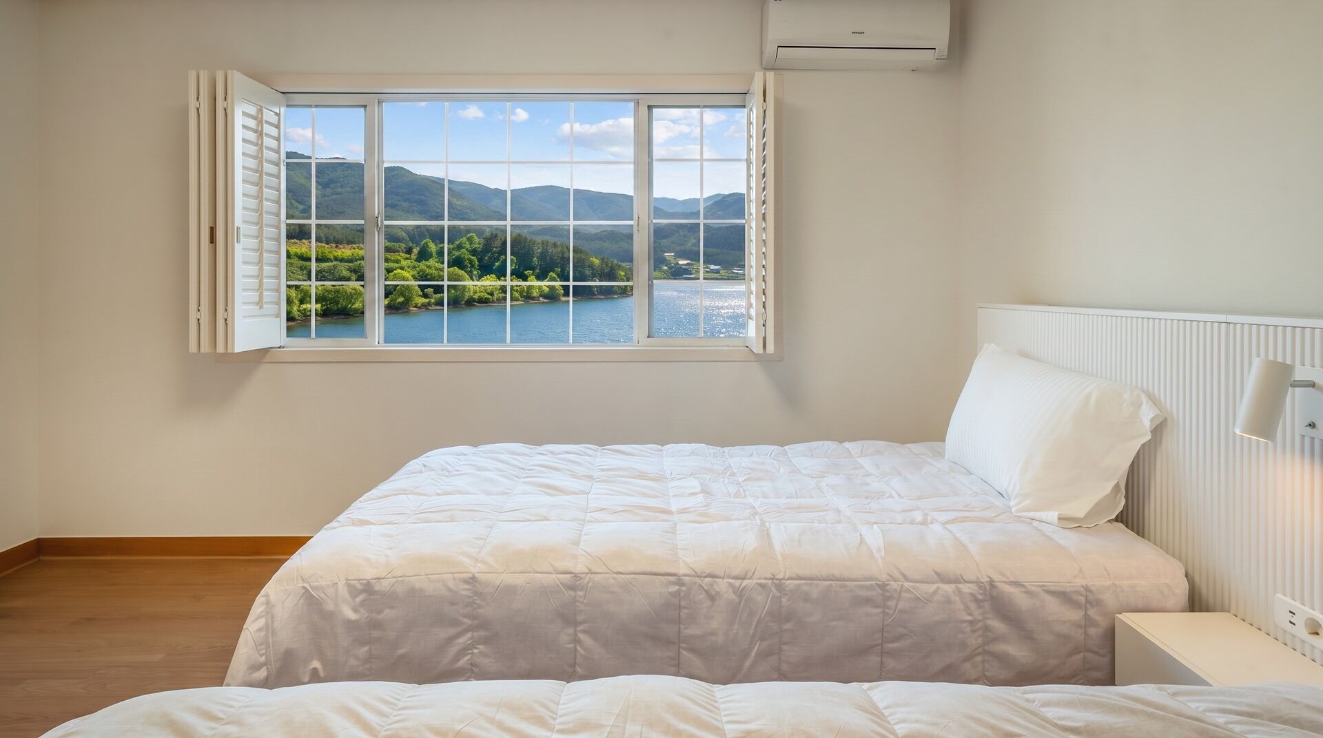 A bedroom with a large window, a bed, a bedside table, and a radiator.