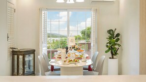 Un comedor con una mesa lista para comer, una planta en maceta y vistas de un paisaje a través de ventanas amplias.