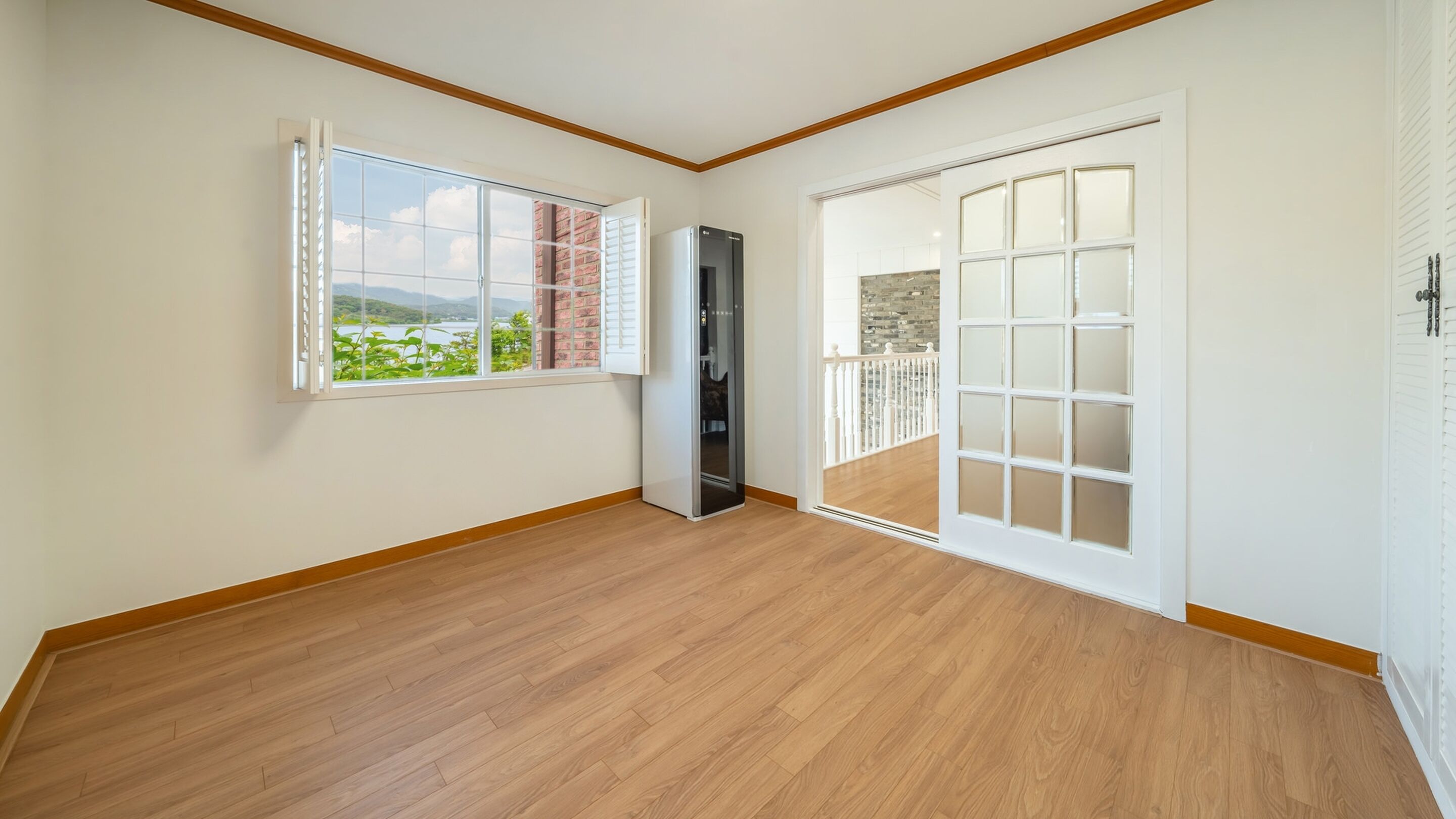 A room with wooden flooring, a sliding glass door, and a refrigerator.