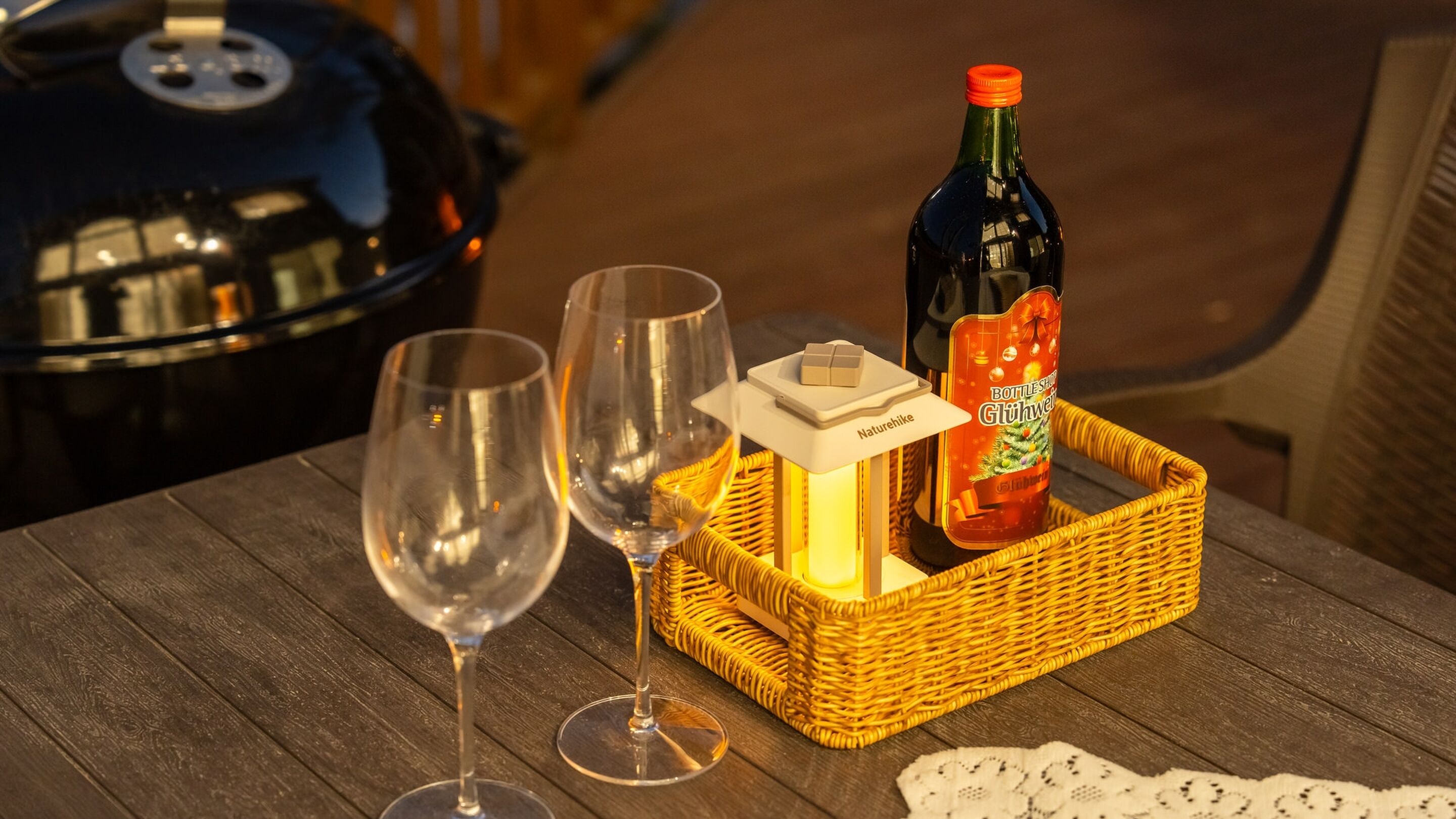 Una mesa con dos copas de vino, una botella de Glühwein y una pequeña caja blanca con una llave.