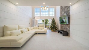 Una sala de estar moderna con un sofá seccional, una chimenea, un árbol de Navidad y un ventanal con vistas.