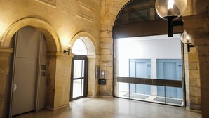 Un pasillo interior con paredes de piedra, puertas abovedadas y un ascensor moderno.