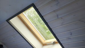 Een kamer met dakraam, een bed en een kledingkast.